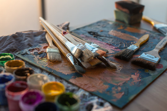 Drawing classes tools in art studio. Angle view photo of paintbrushes lying on palettewith oil paints brushstrokes mixture.