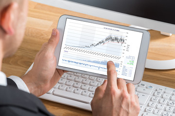 Male Stock Market Broker Working On Digital Tablet