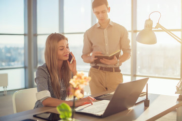 Side view portrait of colleagues in light spacious office busy during working day. Businesswoman...