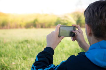 Teenager taking a photograph of beautiful field