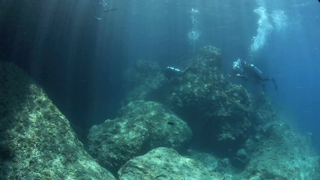 Scuba divers entering underwater tunnel at Gato Island, Philippines 