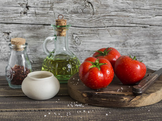 Fresh tomatoes, olive oil and spices on rustic wooden background