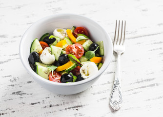 Greek salad on a  light wood background