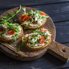 Sandwiches with cheese, tomatoes and arugula on a rustic wooden board. Healthy food