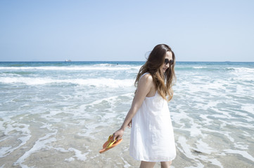 Fototapeta na wymiar Woman wearing a white dress is walking the beach
