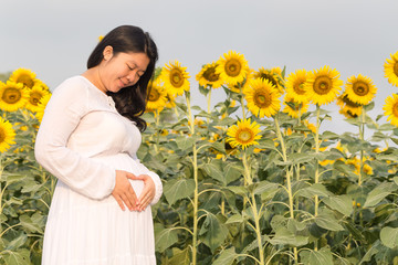 Pregnant woman holding belly in the flower garden.