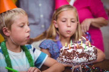 Siblings blowing birthday candles 