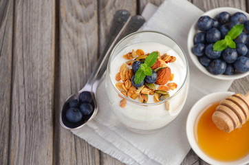 Dessert with homemade granola, yogurt and blueberries on rustic background, top view, copy space