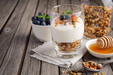 Dessert with homemade granola, yogurt and blueberries on rustic background, selective focus, copy space