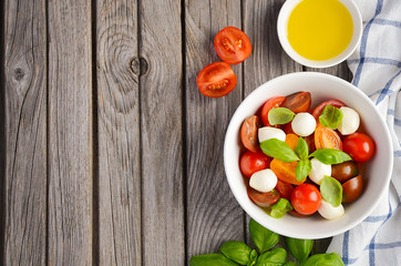 Italian Caprese salad with cherry tomatoes, small mozzarella and fresh basil, top view, copy space
