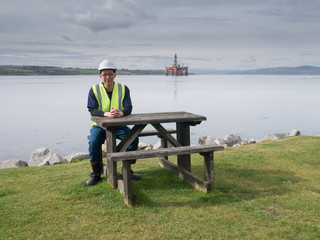 An asian engineer sitting on the desk in front of semi submersib