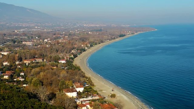 Pan left extreme long shot from turqoise blue sea and golden beaches to snow capped Mount Olumpus
