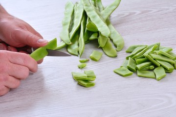 Unrecognizable man cutting green peas