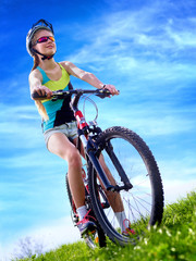 Bikes cycling girl. Girl rides bicycle aganist blue sky . Girl in cycling. Cycling is good for health. Cyclist looking up on blue sky.