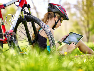 Bikes cycling girl. Girl rides bicycle. Girl in cycling sitting near bicycle and watch pc tablet....