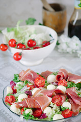 Summer salad with mini mozzarella, cherry tomatoes, lettuce and prosciutto