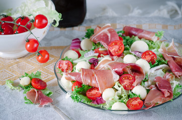 Summer salad with mini mozzarella, cherry tomatoes, lettuce and prosciutto
