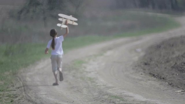 Caucasian boy playing with a model airplane. Portrait of a child with a wooden plane in a field. Boy in nature plays with the layout of the aircraft.
