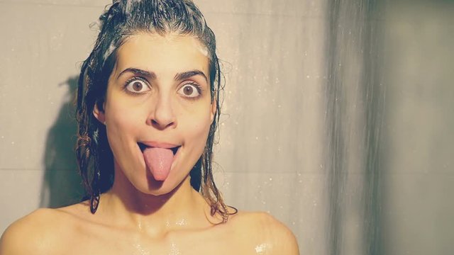 Funny girl making faces washing long hair with shampoo slow motion