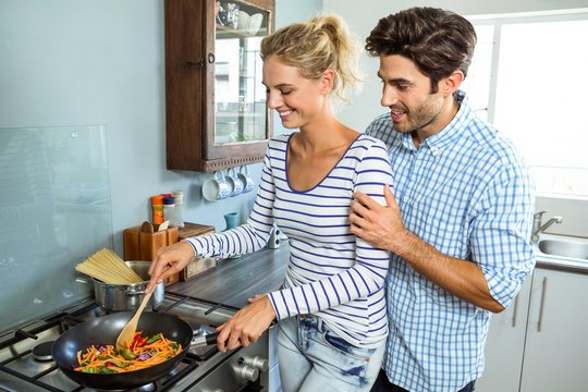 Young couple preparing food together in kitchen 
