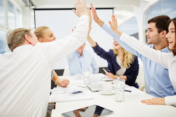 Hände geben sich High Five beim Business Meeting