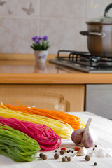 Multicolored pasta on a wooden table in the kitchen background