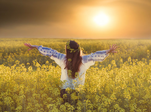 Portrait of a young woman in a rapeseed field. Young girl wearing traditional romanian blouse