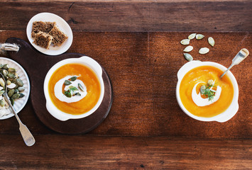 Pumpkin soup with sour cream and seeds, top view with free text space.