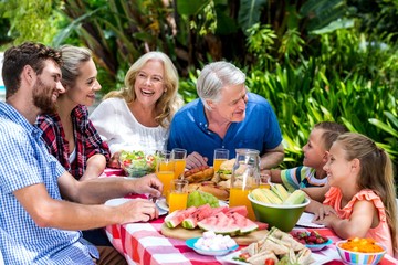 Happy family having food at table in yard 