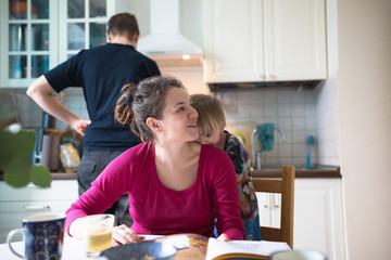 happy family at home kitchen together read book with toddler boy
