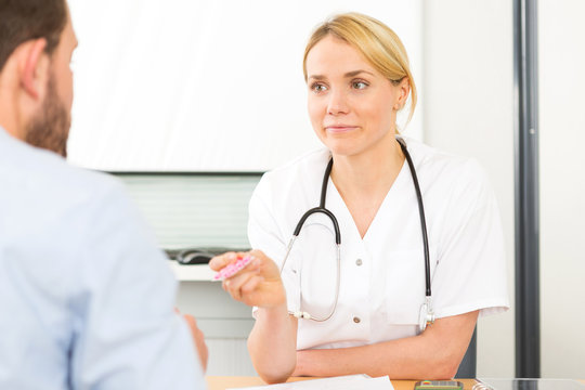 Young attractive woman doctor giving pills to a patient