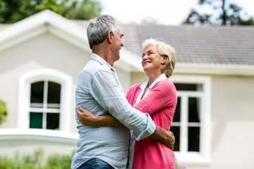 Smiling senior couple against house at yard 