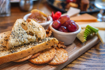 Bread, cheese, cracker, and fruit platter on a wooden board