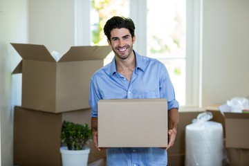 Young man standing with unpacking carton boxes in house