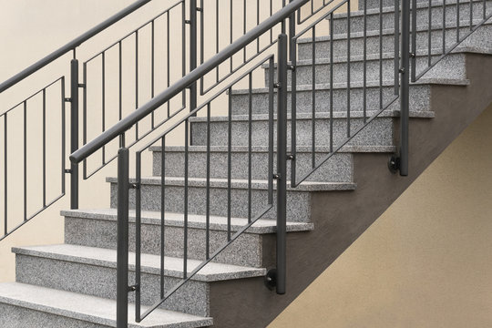 Freitragende Außtreppe mit Auflage aus schwarzweißem Granit und Treppengeländer aus Eisen mit Rostschutzfarbe
