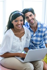 Young couple sitting on bed and using laptop