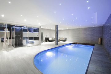Relaxing indoor swimming pool with lighting and a corner for res
