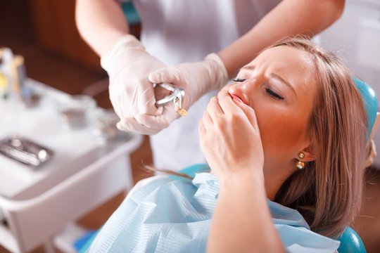 Doctor dentist treats teeth of a beautiful young girl patient. The girl on reception at the dentist. Girl patient pulled tooth.