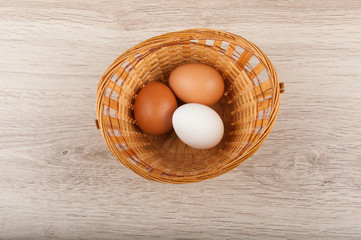 Three eggs in wicker basket. Top view