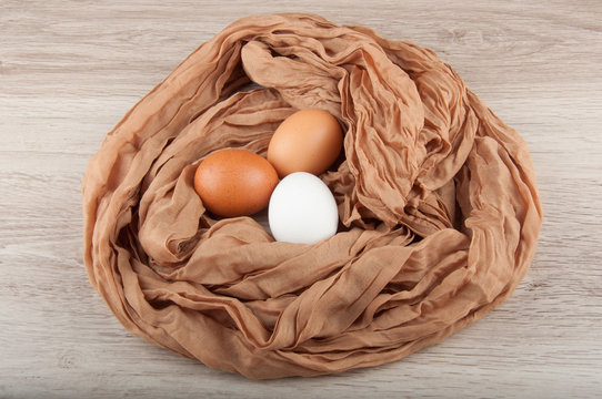 Three chicken eggs in nest made of cloth sack
