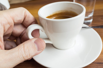 Male hand taking a cup of espresso coffee