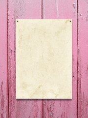 Close-up of one nailed blank old paper sheet frame on pink wooden background
