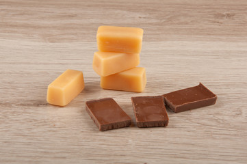 caramel candies and pieces of chocolate on wooden table background