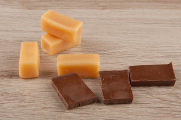 pieces of chocolate  and caramel candies on wooden table background
