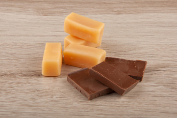 chocolate pieces and caramel candies on wooden table background