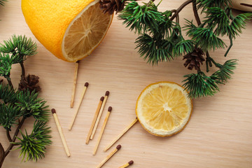 Fototapeta na wymiar Flat lay of yellow objects for your diet such as sliced lemon, matchsticks, surrounded by green pine branches.