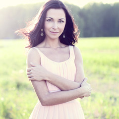 Gorgeous brunette woman with dark hair pink dress summer park green meadow bright sun fashion style concept holiday pose
