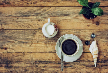 coffee cup, flower in pot, pitcher of milk on wooden table