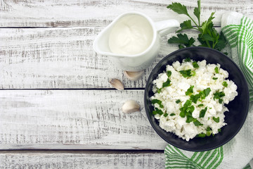 Cottage cheese with chives in black ceramic bowl 