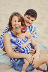 Папа, мама  и маленькая дочь в полосатых майках играют...